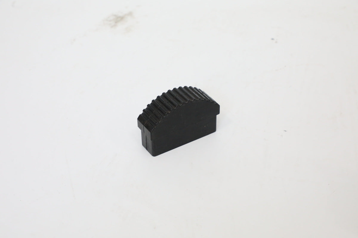 Small black molded block with a curved, ribbed upper surface