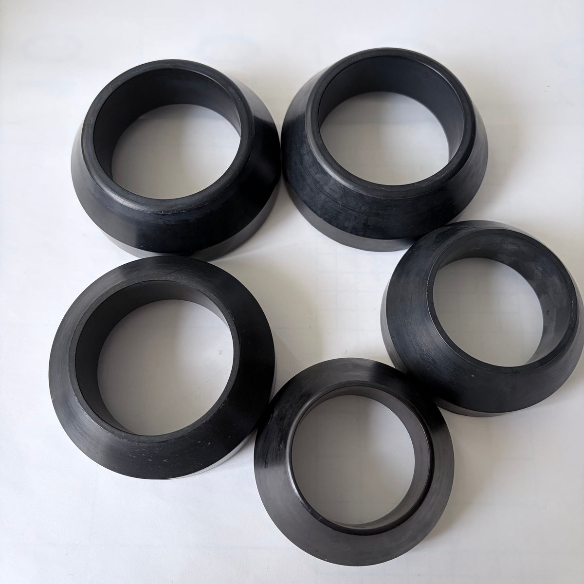 Five black annular components with tapered outer profiles