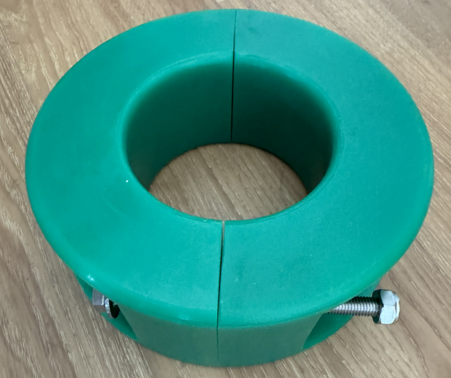 Green split 2 in ID hose bumper with fastening bolt on a wood surface