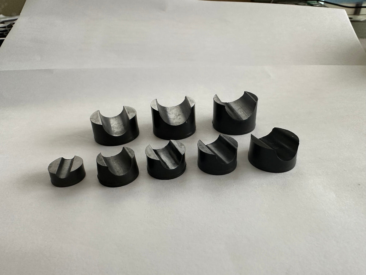 Black molded rubber components arranged on white paper.