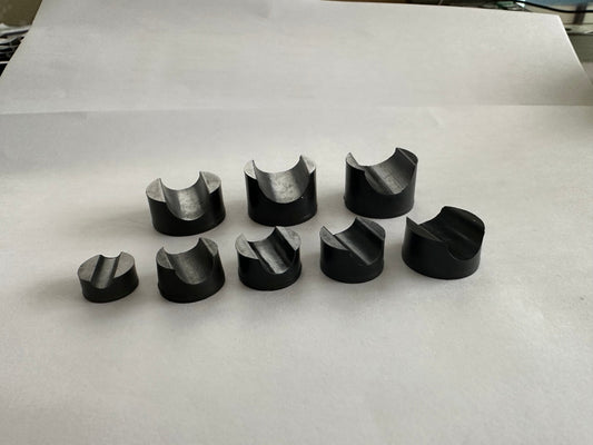 Black molded rubber components arranged on white paper.