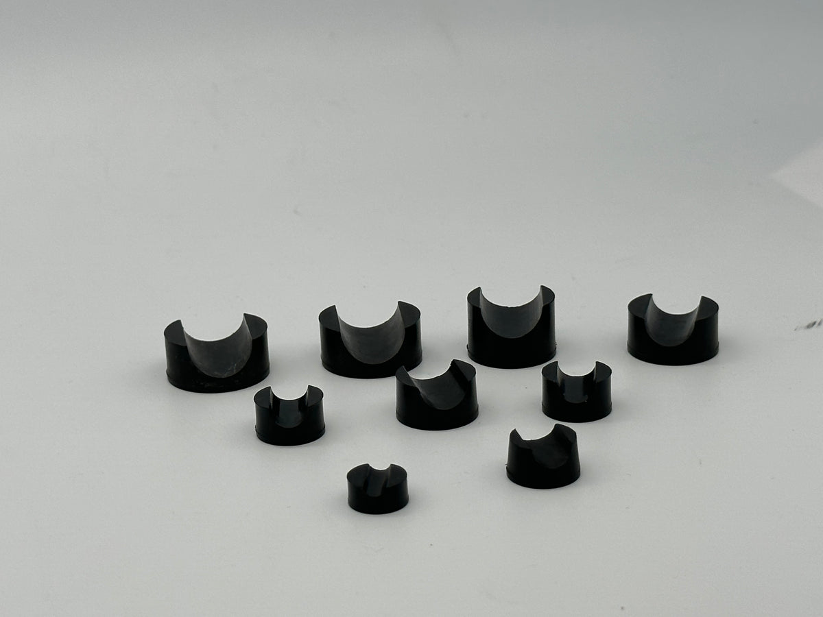 Black molded rubber support blocks with round bases and semicircular cradles