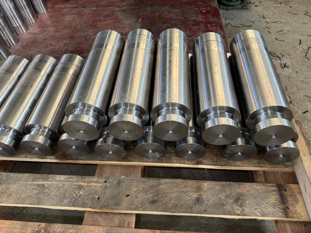 Machined frac pump plunger bodies arranged on a wooden pallet