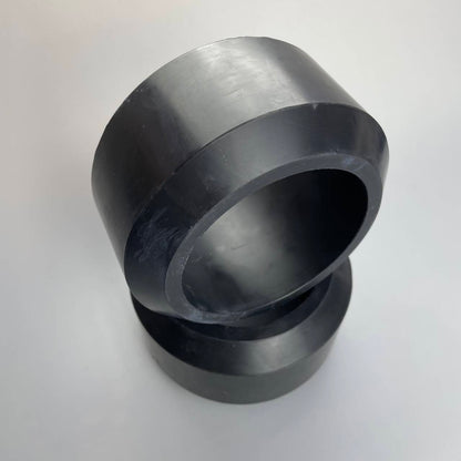 Black oilfield packer elements with wide circular openings on a light background