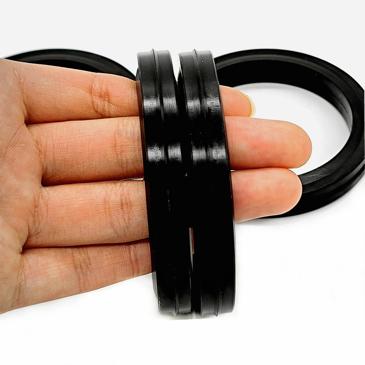 Four black Figure 607 Vee-Lip hammer union seals held edge-on to show the side profile
