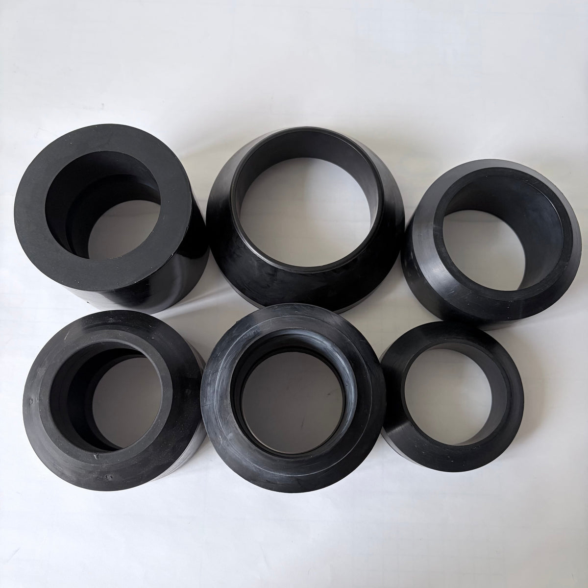 Assorted black oil packer cups showing multiple molded profiles and sizes
