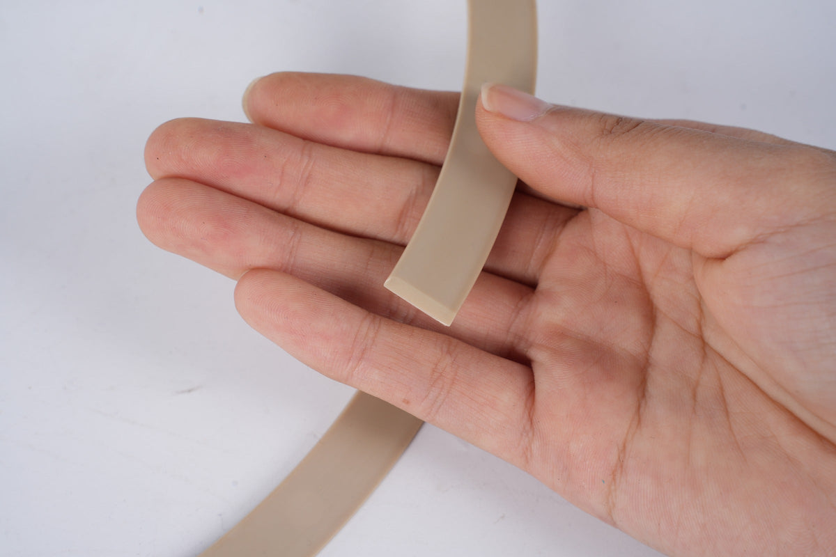 Light-colored custom extruded rubber profile shown in hand for cross-section reference