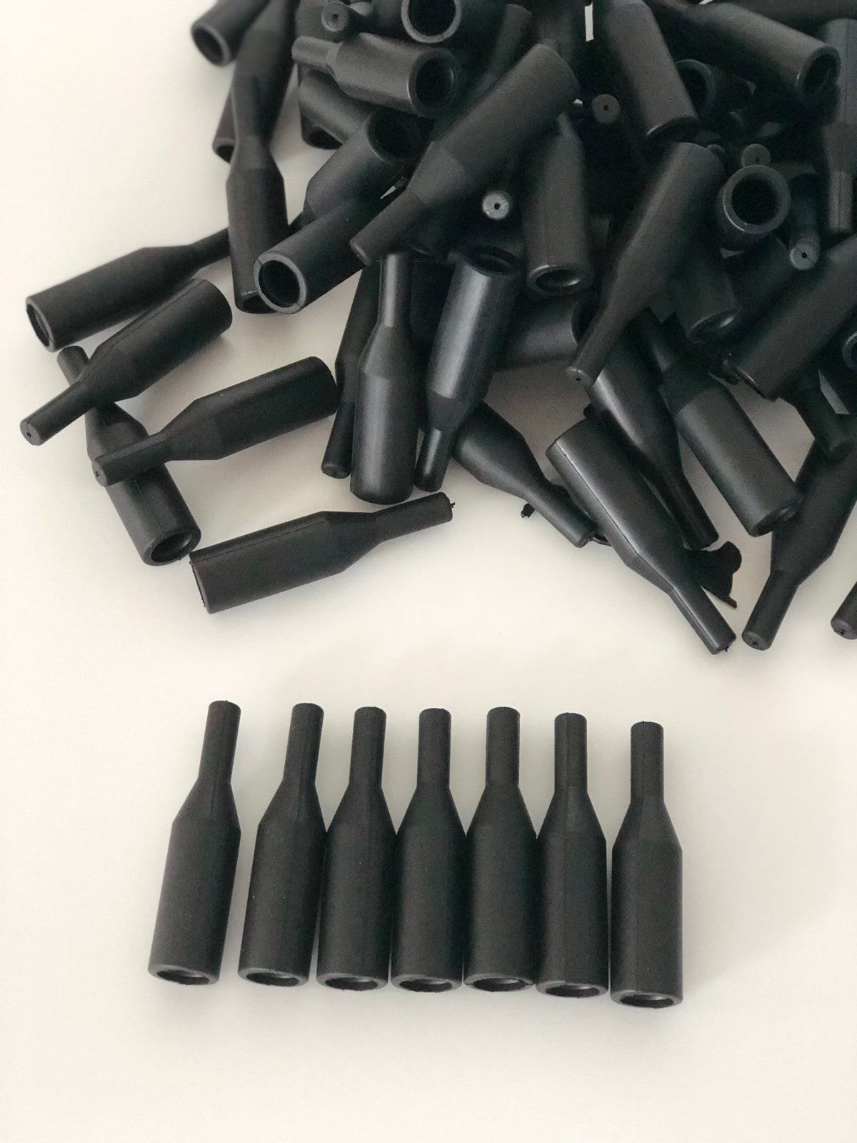 Batch of black custom molded rubber cable and connector boots with tapered outlets