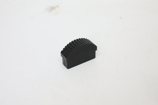 Small black molded block with a curved, ribbed upper surface