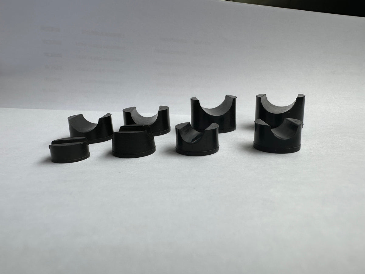 Side detail of black rubber pipe-saddle blocks showing cradle and base profiles