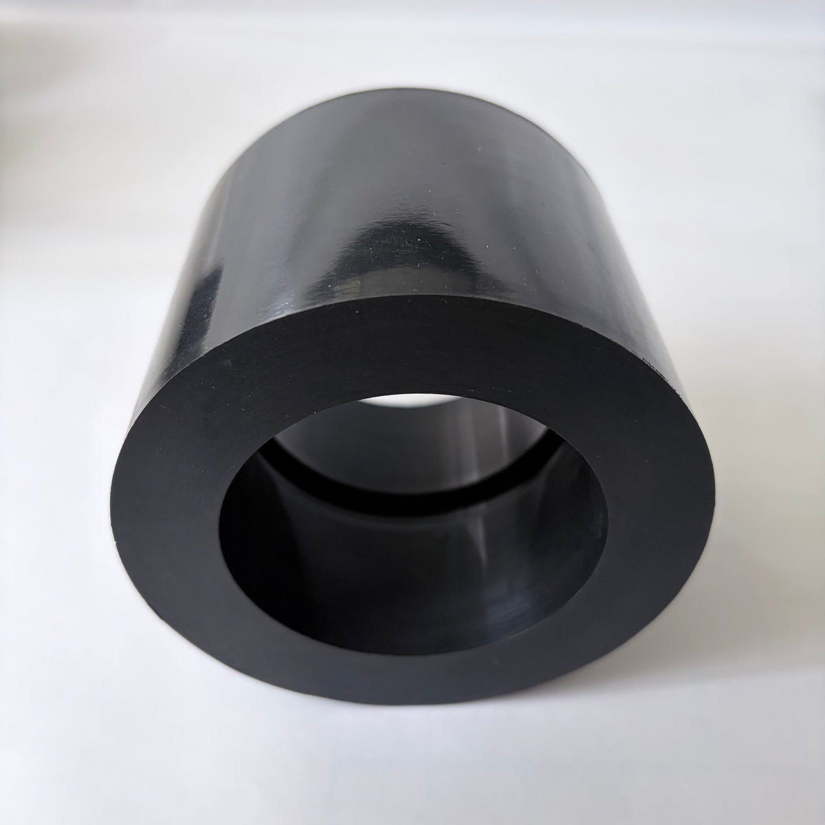 Close-up end detail of a black cylindrical molded rubber component with an open center bore