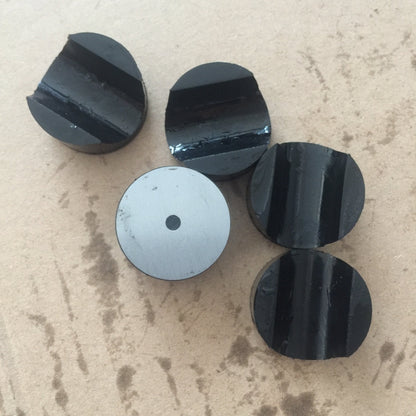 Group of black rubber retaining plugs with molded channels and one metal-backed face